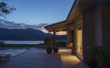 安缦诺怡度假村夜景，建筑外侧灯光温暖，远处湖面在暮色中闪烁。