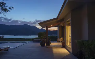 安缦诺怡度假村夜景，建筑外侧灯光温暖，远处湖面在暮色中闪烁。