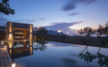 アマノイ・リゾートの水面に映る照明付きパビリオン、夕暮れ時