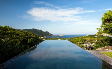 アマノイ リゾートの静寂なプール、緑に囲まれた水面に山々と海が映る。