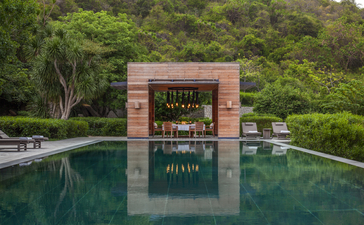 安缦诺怡度假村的水上酒吧，红砖建筑倒映在静谧的池水中，绿树环绕。