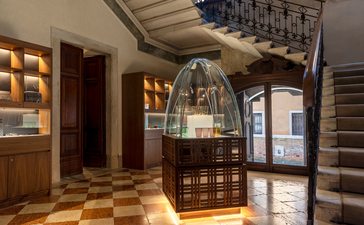 アマン ヴェニスのエッセンシャルズ ブティック。木製のディスプレイケースと照明付きの棚が並ぶ、落ち着いた雰囲気の売店。