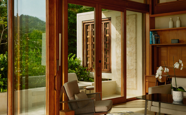 Salon avec portes-fenêtres en bois donnant sur la verdure, à Amanera resort.