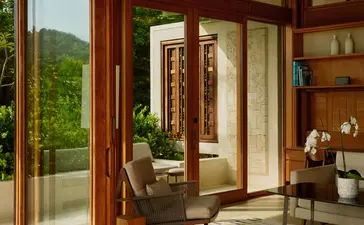Salon avec portes-fenêtres en bois donnant sur les jardins, à Amanera.