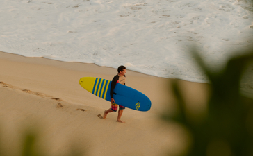 Surfer avec planche bleue sur la plage d'Amanera.