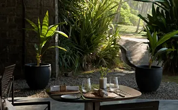 Garden dining area at Amanwella with potted plants and wooden table in Sri Lanka.