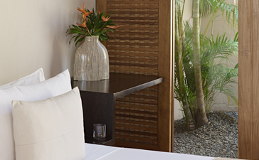 Suite bedroom at Amanwella with white bedding, wooden screen, and view of tropical greenery.
