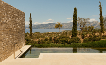 安缦卓熠度假村的豪华泳池馆，设有无边泳池、柏树和远处山景。