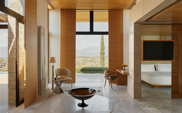 Interno di padiglione con finestre panoramiche, mobili minimalisti e bagno aperto presso il resort Amanzoe.