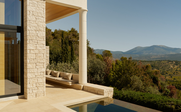 Pool pavilion at Amanzoe with views towards forested hills and mountains beyond.