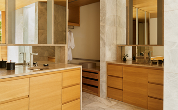 Villa bathroom at Amanzoe resort featuring dual vanities with wooden cabinetry and large mirrors.