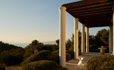 Villa terrace at Amanzoe with stone columns overlooking the Peloponnese landscape at dusk.