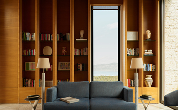 安缦卓熠度假村别墅内，深灰色沙发前方摆放木制书架和照明装置。