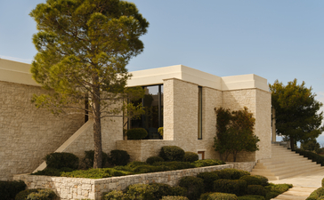Amanzoe villa exterior with stone walls, flat roof, and manicured landscaping overlooking the Peloponnese.