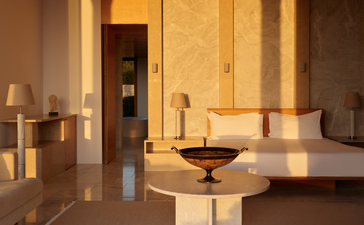 Villa bedroom at Amanzoe resort with warm stone walls and minimalist furnishings.