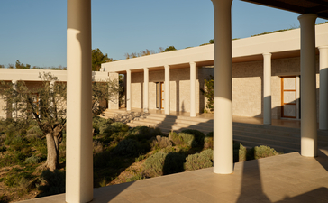 Villa terrace with stone columns overlooking manicured gardens at Amanzoe.
