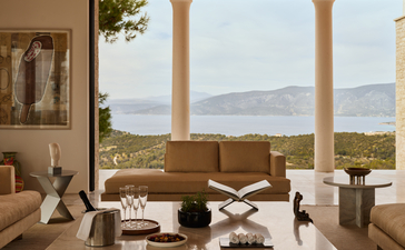 Villa lounge at Amanzoe with columns framing Aegean Sea views and olive groves beyond.