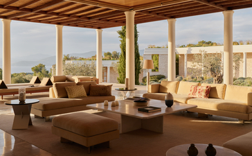 Villa interior at Amanzoe with expansive windows overlooking the Aegean Sea and surrounding landscape.