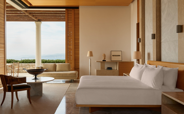 安缦卓熠度假村的宽敞卧室，配有大床、木质框架窗户和爱琴海景观。