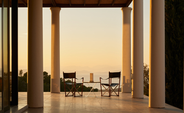 Villa terrace at Amanzoe with chairs overlooking the Aegean Sea at sunset.
