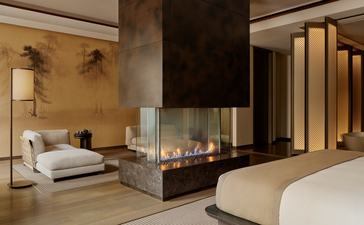 アマン ニューヨークのグランドスイートの寝室。暖色の照明と大理石の壁に囲まれた、モダンで落ち着いた空間。