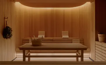 Espace spa chaleureux à Aman New York avec banc en bois, éclairage tamisé et murs ocre.