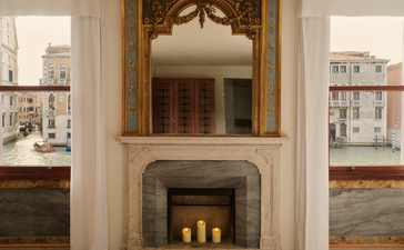 Grand Canal Suite bedroom fireplace at Aman Venice, with ornate mirror and shelving.