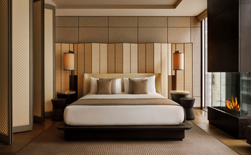 Chambre de la suite deluxe avec lit principal, boiseries murales dorées et mobilier contemporain à l'Aman New York.