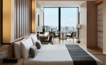 Chambre et salon d'une suite à Aman Tokyo, avec vue sur la ville de Tokyo.
