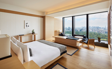 King bed in a spacious bedroom at Aman Tokyo with floor-to-ceiling windows overlooking the garden.