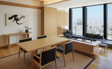 安缦东京酒店大套房的用餐区，配备木质餐桌、现代座椅及城市景观窗户。