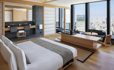 Chambre avec lit king-size, bureau et vue panoramique sur Tokyo à l'Aman Tokyo.
