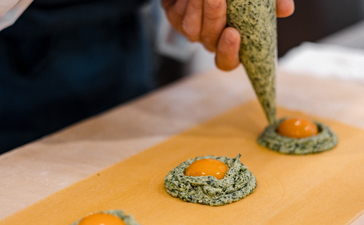 Hands presenting a dish at Aman Tokyo hotel, plating garnished food with precision.