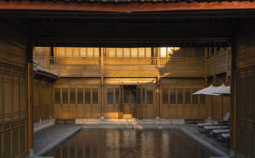Amandayan courtyard at dusk, reflecting golden light on still water beneath a traditional tiled roof.