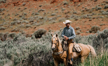 Rider on horseback in sagebrush landscape at Amangani, Jackson Hole.