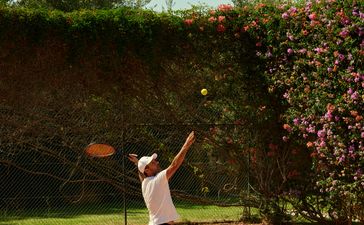 安缦珍纳度假村网球场，运动员在红土球场上挥拍练习。