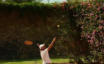 Joueur de tennis en train de servir sur le court à Amanjena.