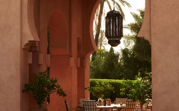 安缦珍纳度假村餐厅泳池露台，红色拱门框景，水池倒影摩洛哥建筑。