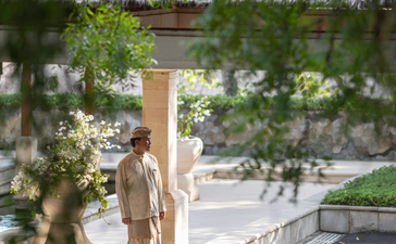 Membro da equipa do Amankila resort em Bali, Indonésia, junto a uma escultura de madeira.