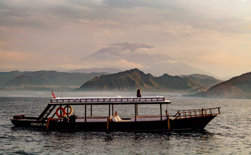Wooden longtail boat on calm waters at sunrise, Amankila.