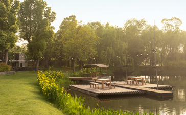 Bamboo rafts moored on a tranquil waterway at Amanyangyun, with manicured lawns and ancient trees lining the banks.