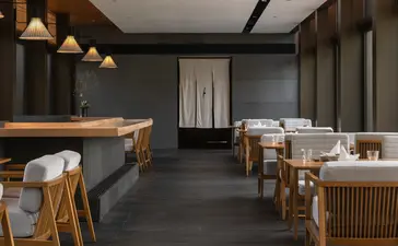 养云安缦度假村的用餐区,木质家具搭配深灰色墙面,吊灯投射温暖光线。