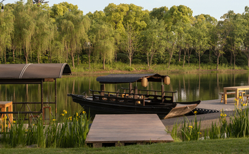 Wooden pavilion and jetty beside still water at Amanyangyun, with forested banks reflected in the lake.