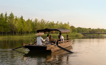 Afternoon tea served on a wooden boat at Amanyangyun, lakeside setting with forested shoreline.
