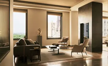 Salon spacieux d'une suite trois chambres à Aman New York, avec mobilier contemporain et grandes fenêtres.