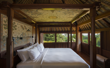 Ayung Suite bedroom at Amandari with bed facing open wooden doors overlooking the forest in Ubud, Bali.
