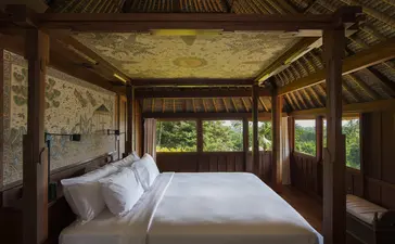 Ayung Suite bedroom at Amandari with bed facing open wooden doors overlooking the forest in Ubud, Bali.