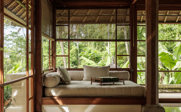 Duplex suite at Amandari with four-poster bed, wooden frame, and garden views through open doors.