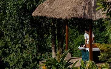 Spa pavilion with thatched roof nestled amongst tropical foliage at Amandari, Ubud, Bali.