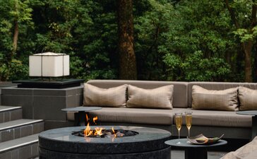 Outdoor aperitif setting at Aman Kyoto with fire pit, seating and verdant garden backdrop.